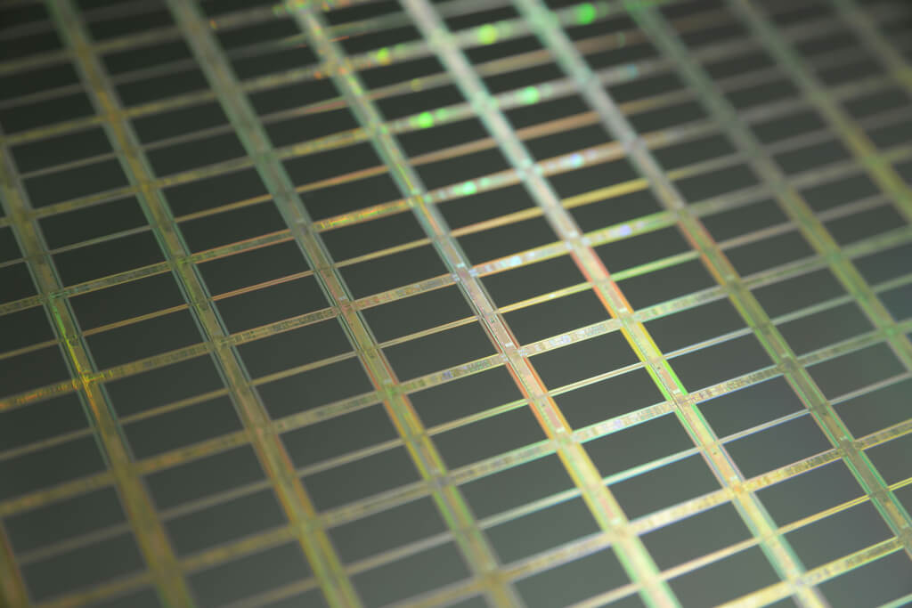 Macroaufnahme eines Silizium-Wafers mit einzelnen Chips und mikroskopischen Transistoren